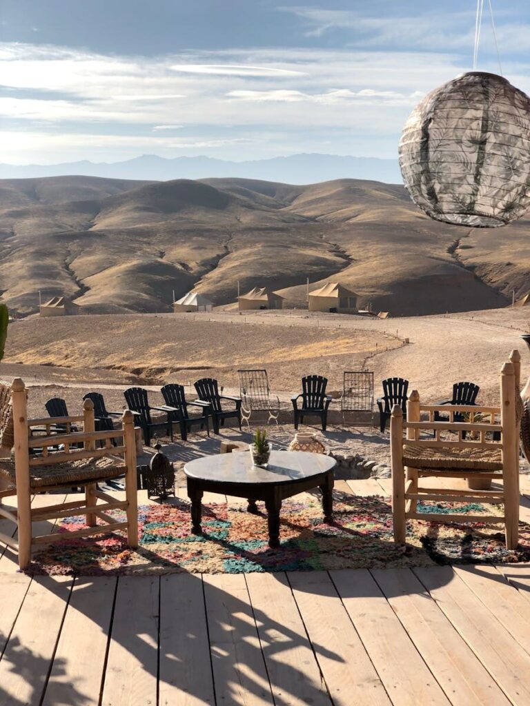 Serene desert camp view with wooden chairs and Moroccan landscape.