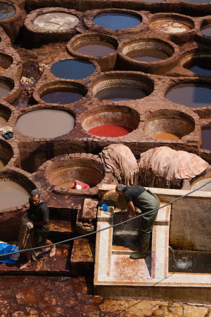 Home Workers at a historic tannery in Fes, Morocco dye fabrics in vibrant hues.