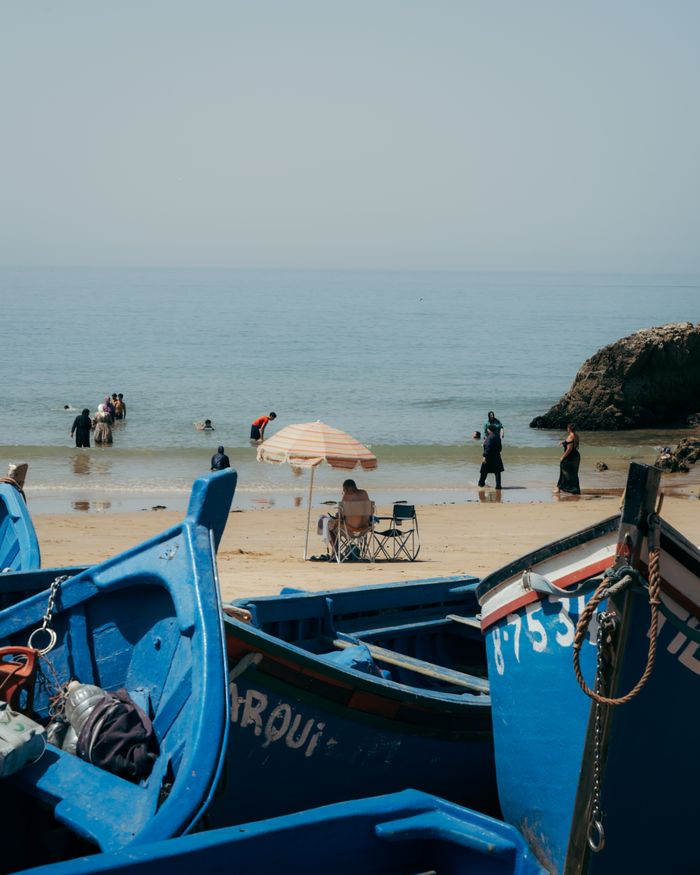 Mastering the First Impression: Your intriguing post title goes here Relaxing scene of a beach with blue fishing boats, sunbathers, and swimmers enjoying a sunny day.